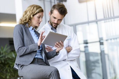 Businesswoman with tablet and doctor talking in hospital stock photo