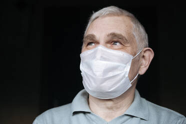 Portrait of senior man wearing a mask at home - EYAF00995