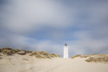 Dänemark, Romo, Blavand, Wolken über sandigem Küstenstrand mit Leuchtturm im Hintergrund - ASCF01187