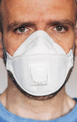 Portrait of man wearing respirator mask - JCMF00493