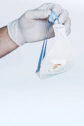 Hand in protective glove holding respirator mask - JCMF00498