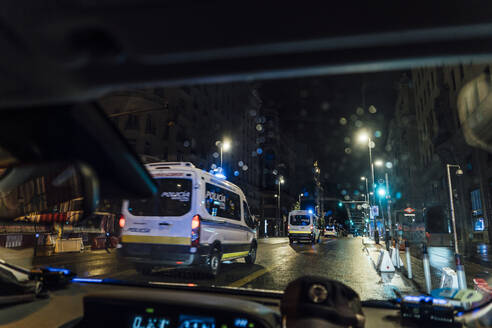 Spanien, Madrid, Innenraum eines Autos, das nachts hinter der Polizei fährt - OCMF01152