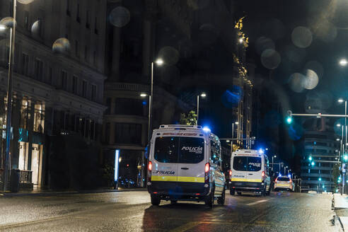 Spanien, Madrid, Polizeiautos fahren nachts durch die Stadt - OCMF01153