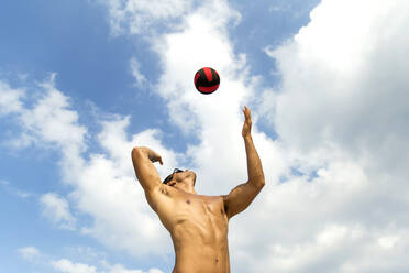 Low Angle View of Fit Shirtless Young Man Spielen mit Ball gegen den Himmel - EYF01815