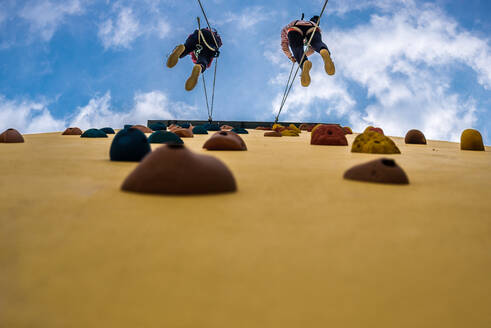 Low Angle View of People Climbing On Wall Against Sky - EYF01825