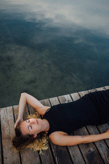 Woman Lying Down On Pier By River Against Sky - EYF01946