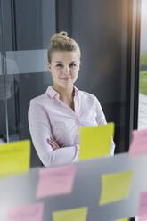 Young businesswoman, standing in office in front of adhesive notes - BMOF00336