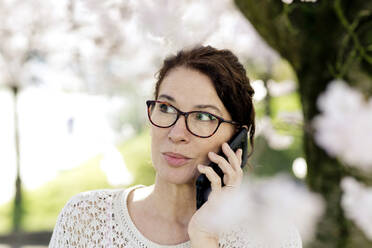 Porträt einer reifen Frau am Telefon im Frühling - FLLF00443