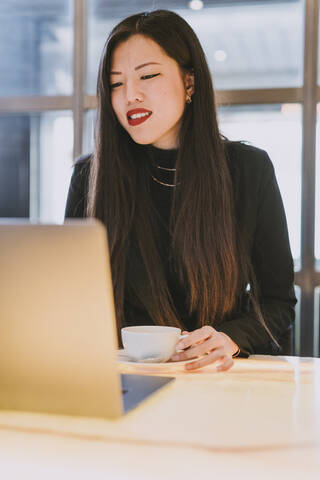 Lächelnde Geschäftsfrau mit Laptop in einem Cafe, lizenzfreies Stockfoto
