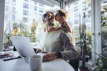 Little boy hugging father from behind, while working from home - MFF05167