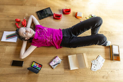 Girl lying on floor, with eyes closed, surrounded by play equipment - SARF04497