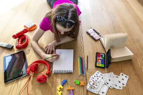 Girl lying on floor with play equipment, drawing on pad stock photo