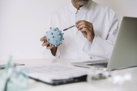 Nahaufnahme eines Wissenschaftlers, der das Modell des Coronavirus in einer Videokonferenz am Schreibtisch erklärt, lizenzfreies Stockfoto
