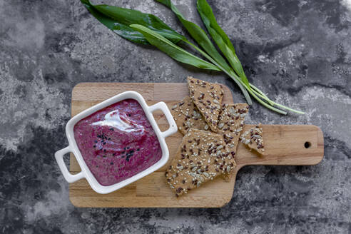 Cutting board, bowl of beetroot dip, crispbread and fresh ramson - SARF04508