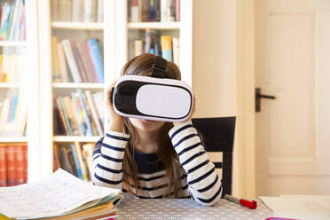 Girl sitting at table at home using virtual reality glasses - LVF08706