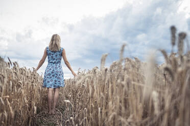 Back view of barefoot woman standing in a wheat field - WFF00294