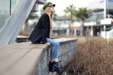 Blond young woman relaxing on a bench - JSRF00953