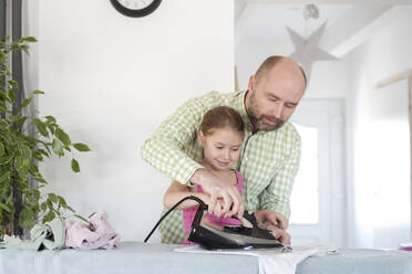 Father and daughter ironing together at home - VYF00098