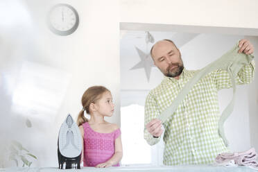 Father and daughter ironing together at home - VYF00101