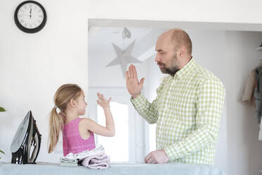 Vater und Tochter geben sich nach dem Bügeln zu Hause die Hand - VYF00105