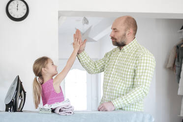 Vater und Tochter geben sich nach dem Bügeln zu Hause die Hand - VYF00106