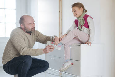 Vater hilft Tochter beim Anziehen der Schuhe zu Hause - VYF00110