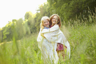 Portrait of happy girls wrapped in blanket on a meadow - AUF00203