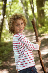 Portrait of boy with wood stick walking in forest - AUF00209