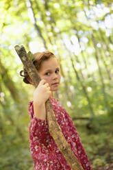 Portrait of girl with wood stick walking in forest - AUF00210