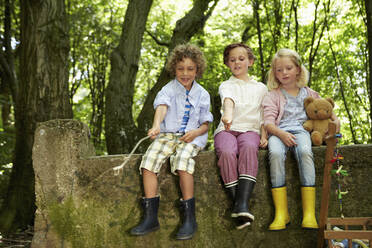 Kinder sitzen auf einer Steinmauer im Wald - AUF00221