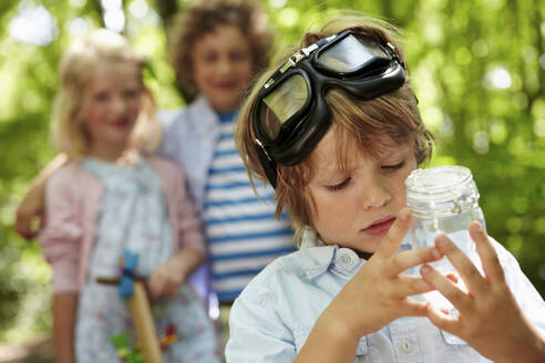 Porträt eines Jungen, der ein Glas im Wald hält - AUF00223