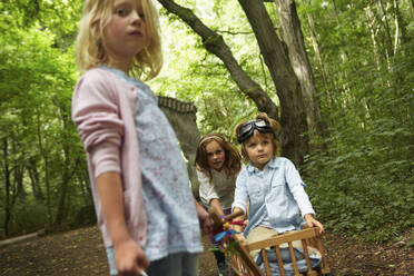 Kinder mit Bollerwagen spielen im Wald - AUF00227