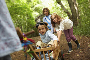 Kinder mit Bollerwagen spielen im Wald - AUF00228