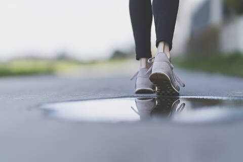 Joggerin, Spiegelung der Laufschuhe in einer Pfütze, lizenzfreies Stockfoto