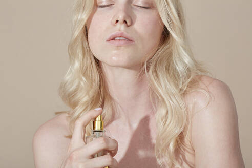 Blonde junge Frau trägt Parfüm auf - PGCF00077