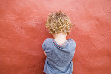 Rückenansicht eines kleinen Jungen vor einer roten Wand - IHF00301