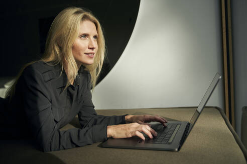 Blonde Frau auf dem Sofa liegend mit Laptop - PNEF02509