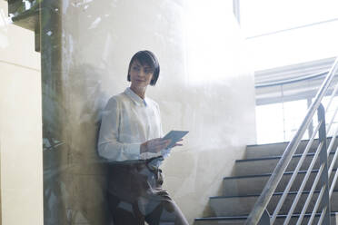 Businesswoman using digital tablet in hallway - JOSEF00183