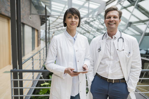 Zwei Ärzte stehen im Atrium und halten ein digitales Tablet, lizenzfreies Stockfoto