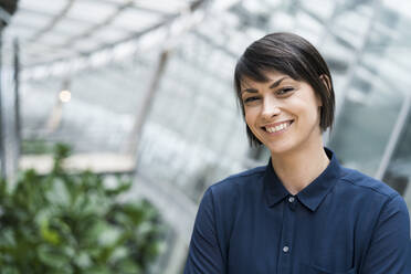 Portrait of smiling businesswoman in sustainable office building - JOSEF00244