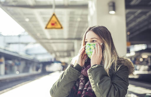 Porträt einer jungen Frau mit Maske auf einem Bahnsteig - BFRF02204