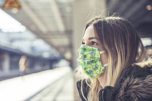 Porträt einer jungen Frau mit Maske auf einem Bahnsteig - BFRF02206