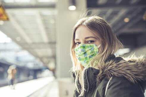 Porträt einer jungen Frau mit Maske auf einem Bahnsteig - BFRF02207