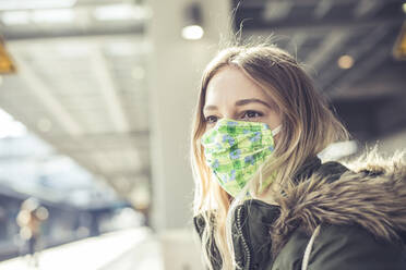Porträt einer jungen Frau mit Maske auf einem Bahnsteig - BFRF02208