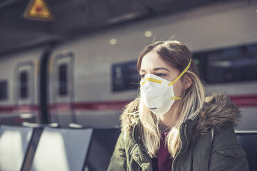 Portrait of young woman wearing respirator mask at station platform - BFRF02209