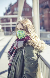 Portrait of young woman wearing mask on a bridge in the city - BFRF02216