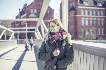 Porträt einer jungen Frau mit Maske auf einer Brücke in der Stadt - BFRF02217