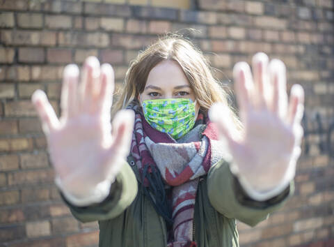 Portrait of young woman wearing mask raising her hands stock photo