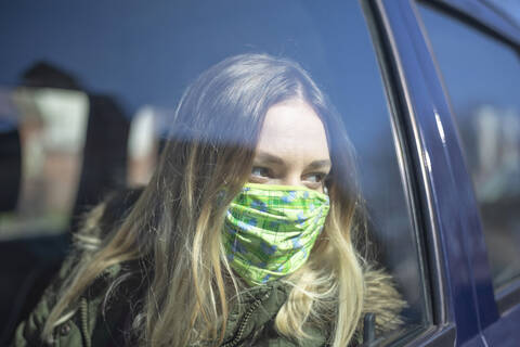 Portrait of young woman wearing mask in car stock photo