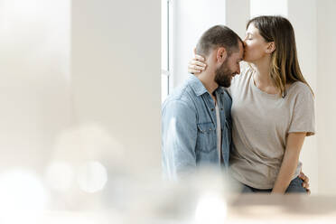 Affectionate couple in love at window in their home - SBOF02161